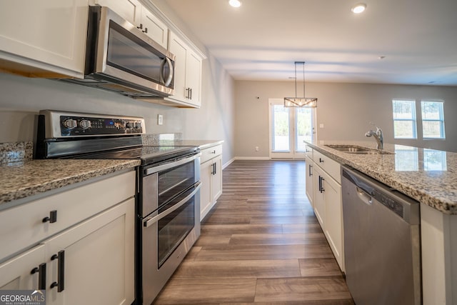 kitchen featuring white cabinets, stainless steel appliances, light stone counters, and sink