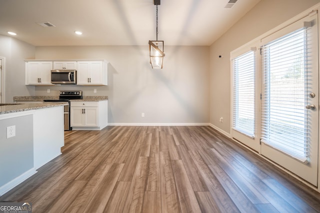 kitchen featuring light stone countertops, hanging light fixtures, stainless steel appliances, wood-type flooring, and white cabinets