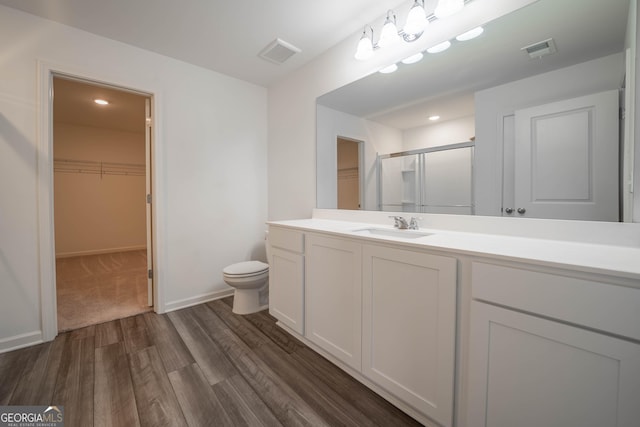 bathroom with toilet, a shower with door, vanity, and hardwood / wood-style flooring