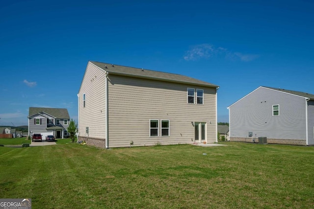 back of house with central air condition unit and a yard