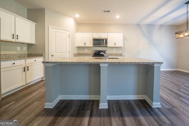 kitchen with dark hardwood / wood-style flooring, light stone counters, white cabinetry, and an island with sink