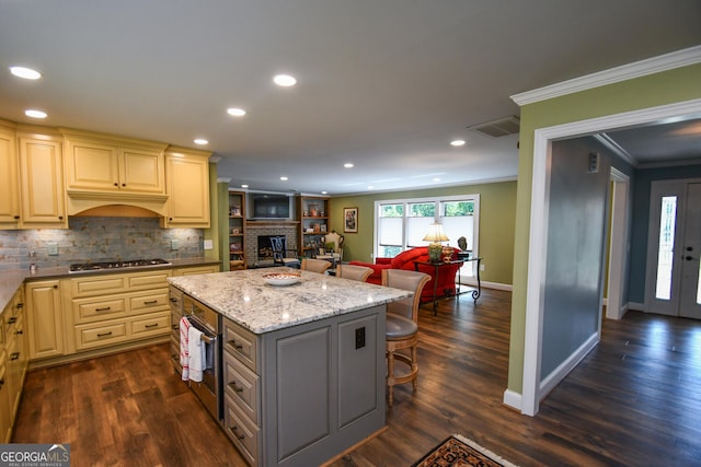 kitchen featuring dark hardwood / wood-style flooring, stainless steel appliances, ornamental molding, a kitchen bar, and a center island