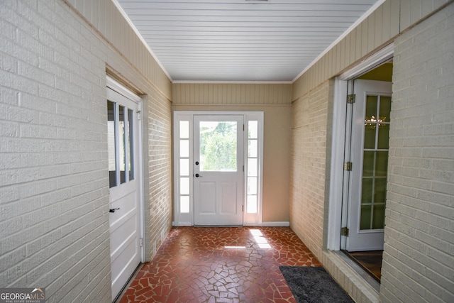 entryway featuring brick wall and crown molding