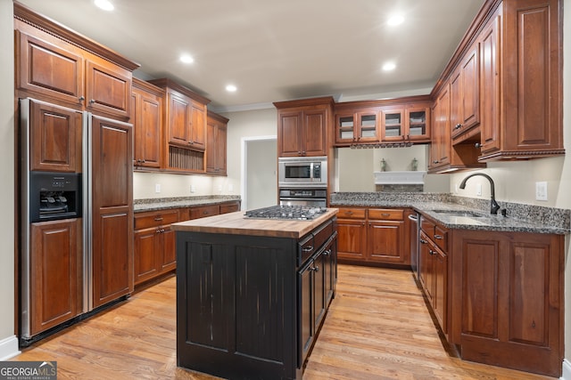 kitchen with ornamental molding, light hardwood / wood-style floors, sink, and built in appliances