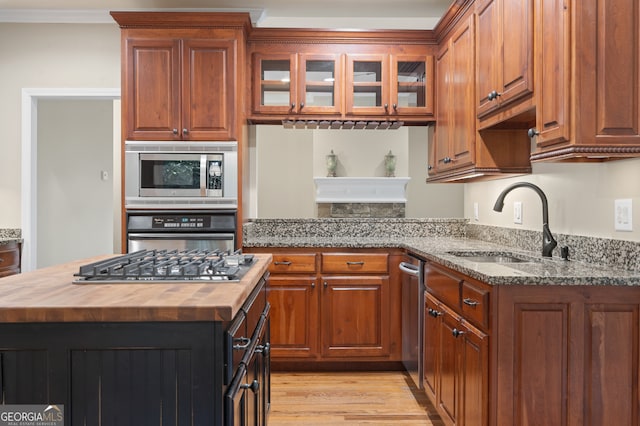 kitchen featuring stainless steel appliances, sink, crown molding, wood counters, and light hardwood / wood-style flooring