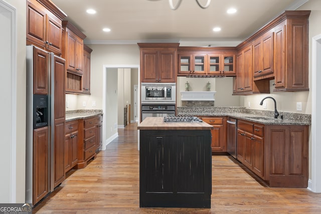 kitchen featuring ornamental molding, light wood-type flooring, sink, and built in appliances