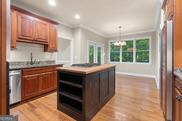 kitchen with appliances with stainless steel finishes, butcher block countertops, sink, and light hardwood / wood-style flooring