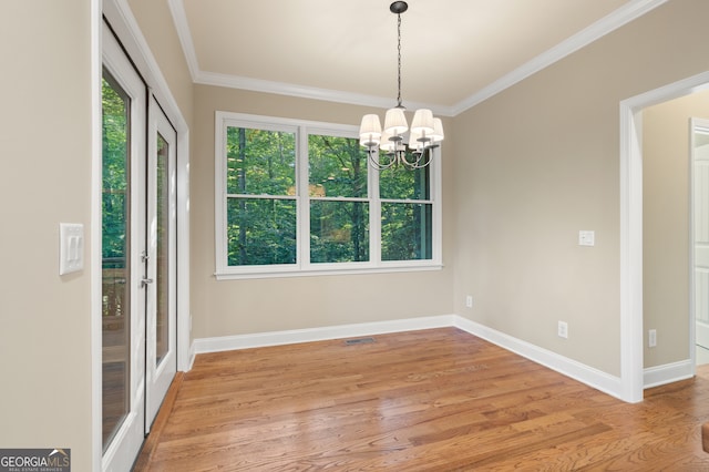 unfurnished dining area with an inviting chandelier, light hardwood / wood-style flooring, and crown molding