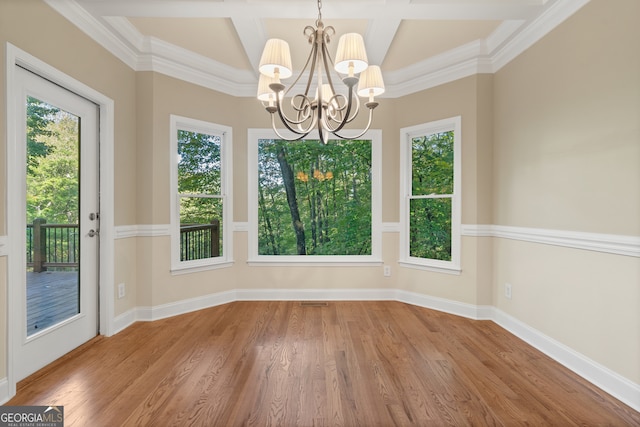 unfurnished dining area featuring wood-type flooring, ornamental molding, a notable chandelier, and coffered ceiling