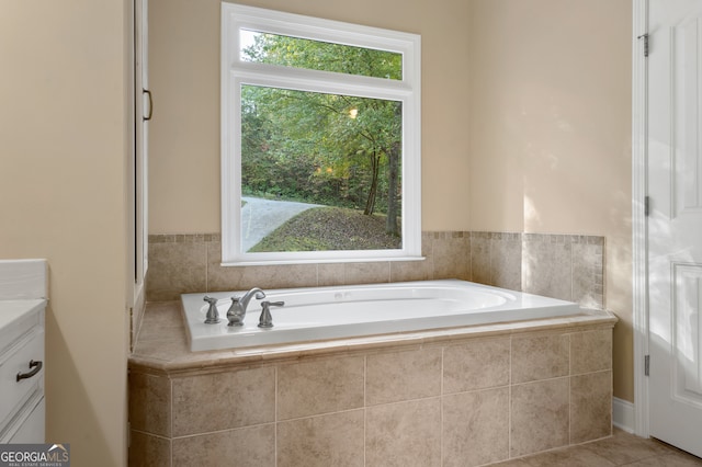 bathroom with vanity, tiled bath, tile patterned flooring, and plenty of natural light