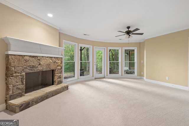 unfurnished living room featuring a stone fireplace, ceiling fan, crown molding, and carpet floors