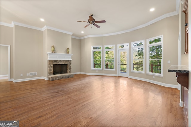 unfurnished living room featuring a stone fireplace, light hardwood / wood-style flooring, ceiling fan, and crown molding