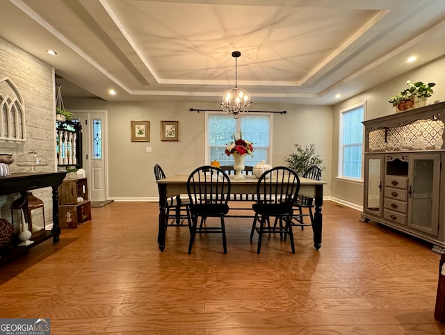 dining area featuring a raised ceiling, hardwood / wood-style floors, and a notable chandelier