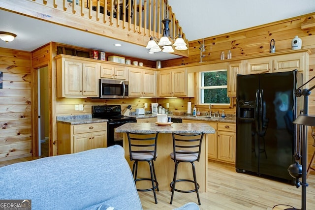 kitchen with a center island, light hardwood / wood-style flooring, black appliances, light brown cabinets, and decorative light fixtures