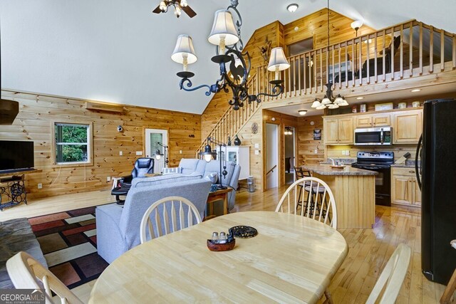 dining area featuring a notable chandelier, light hardwood / wood-style flooring, wooden walls, and high vaulted ceiling