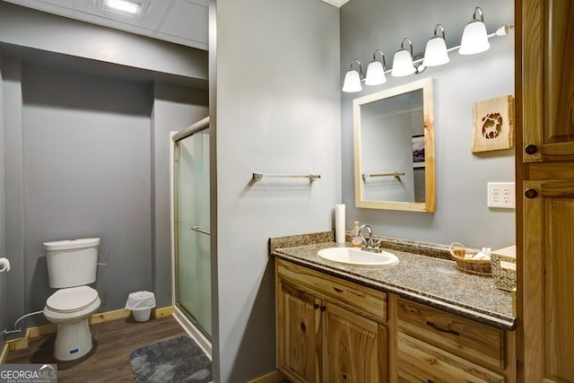 bathroom with wood-type flooring, a drop ceiling, walk in shower, vanity, and toilet