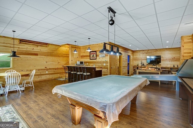 game room with wood walls, a paneled ceiling, and dark hardwood / wood-style flooring