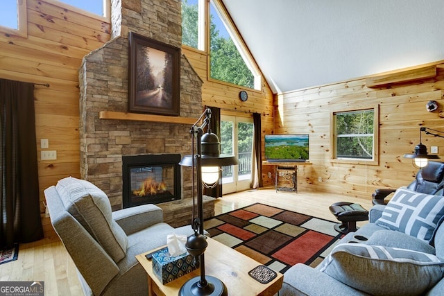 living room featuring high vaulted ceiling, wood walls, light hardwood / wood-style flooring, and a fireplace