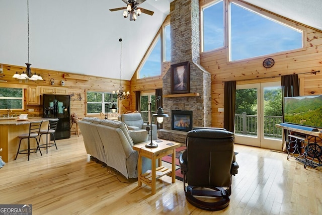 living room featuring high vaulted ceiling, wooden walls, light hardwood / wood-style floors, and a healthy amount of sunlight