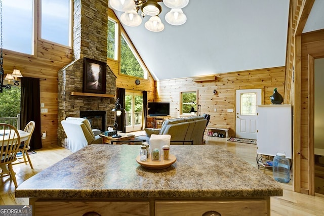 kitchen with high vaulted ceiling, light wood-type flooring, and wood walls