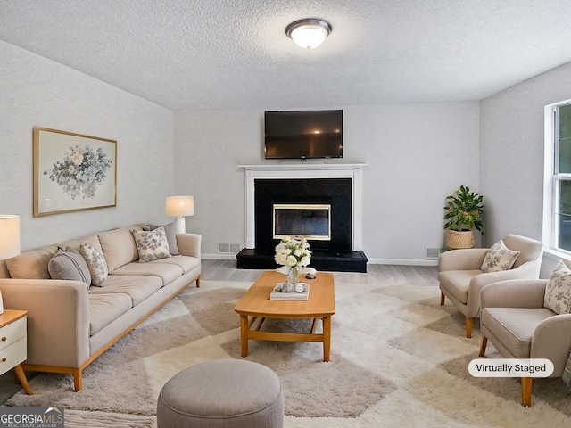 living room featuring a premium fireplace, light hardwood / wood-style floors, and a textured ceiling