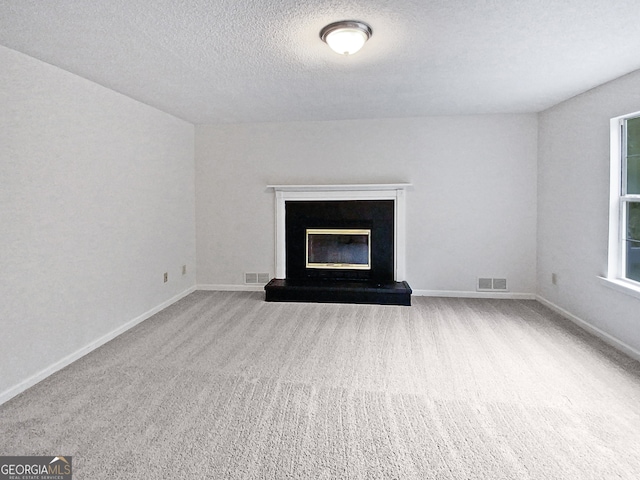 unfurnished living room featuring light carpet and a textured ceiling