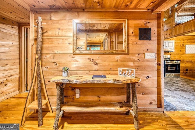 interior space with stainless steel range, wood ceiling, wood walls, and hardwood / wood-style floors