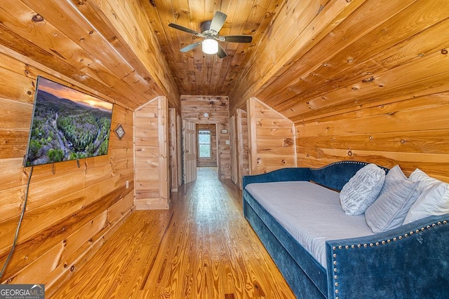 bedroom featuring ceiling fan, lofted ceiling, wood walls, hardwood / wood-style flooring, and wooden ceiling