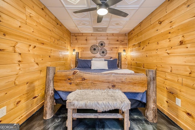 bedroom with ceiling fan and wood walls