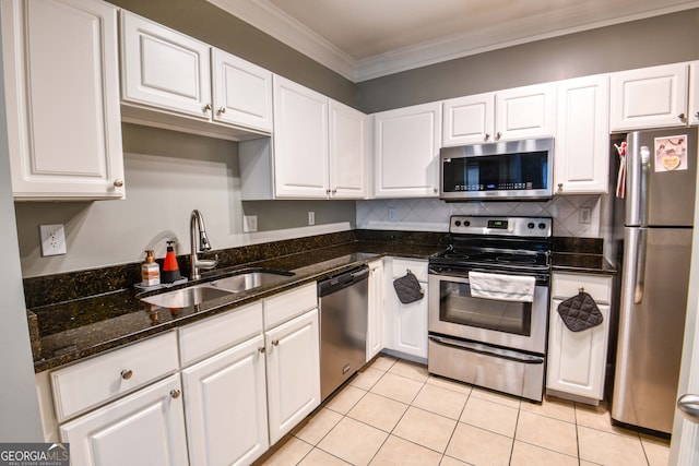 kitchen with sink, white cabinets, appliances with stainless steel finishes, light tile patterned floors, and ornamental molding