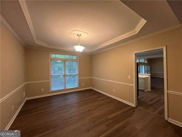 empty room with crown molding, a tray ceiling, and dark hardwood / wood-style floors