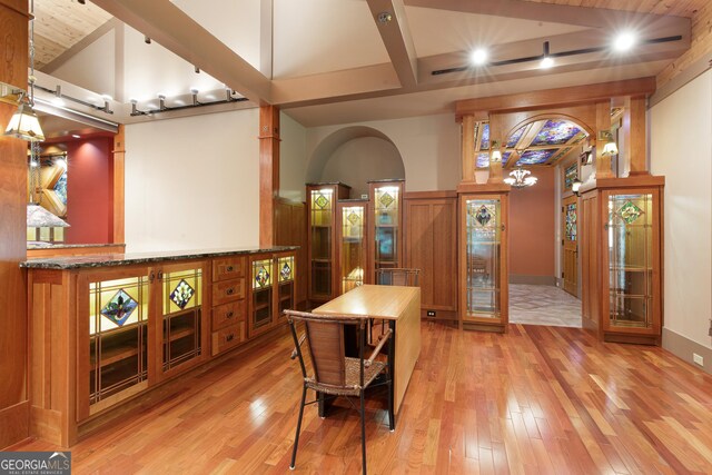 interior space featuring vaulted ceiling with beams, a notable chandelier, and hardwood / wood-style flooring