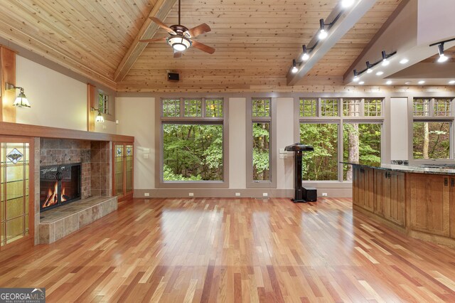 unfurnished living room with a fireplace, wood ceiling, beam ceiling, and light hardwood / wood-style flooring