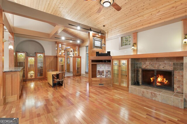 unfurnished living room featuring high vaulted ceiling, beamed ceiling, wood ceiling, light hardwood / wood-style floors, and a tile fireplace