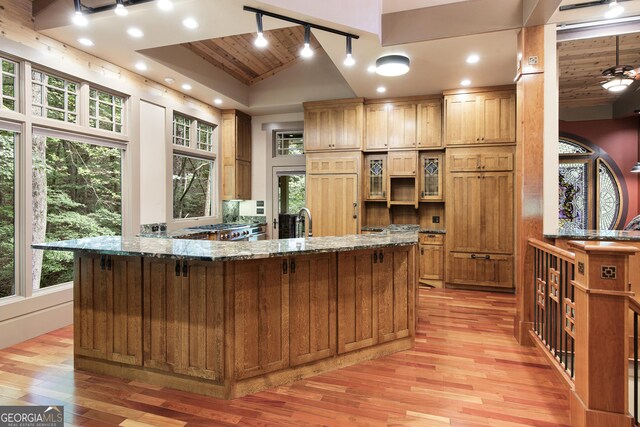 kitchen with vaulted ceiling, stone counters, wood ceiling, and light hardwood / wood-style floors