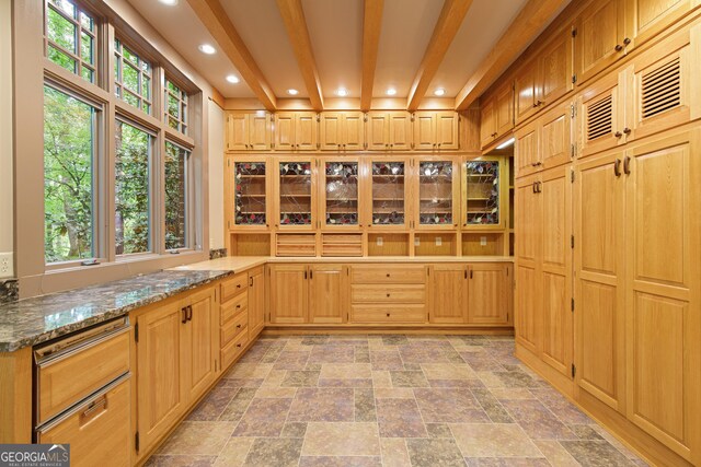 kitchen with light brown cabinetry, light stone counters, beam ceiling, and a wealth of natural light