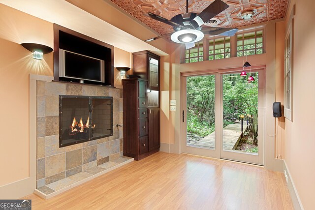 unfurnished living room featuring a tile fireplace, hardwood / wood-style floors, and ceiling fan