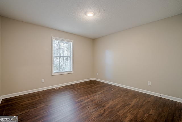 unfurnished room with a textured ceiling and dark hardwood / wood-style floors