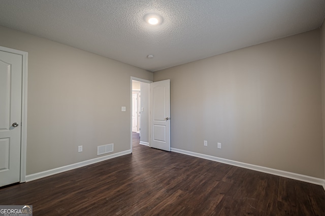 unfurnished room with a textured ceiling and dark hardwood / wood-style floors