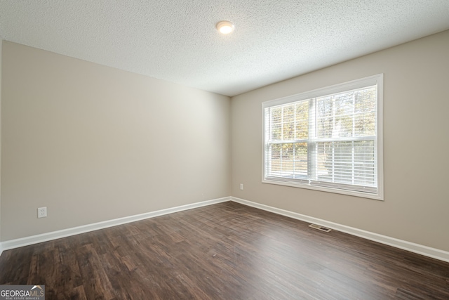 unfurnished room with dark hardwood / wood-style floors and a textured ceiling