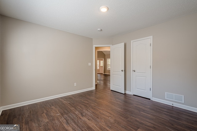 unfurnished bedroom with a textured ceiling and dark wood-type flooring