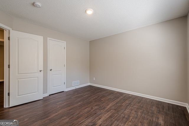 unfurnished bedroom featuring a textured ceiling and dark hardwood / wood-style flooring