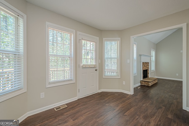 foyer entrance with dark hardwood / wood-style floors, a healthy amount of sunlight, and a fireplace