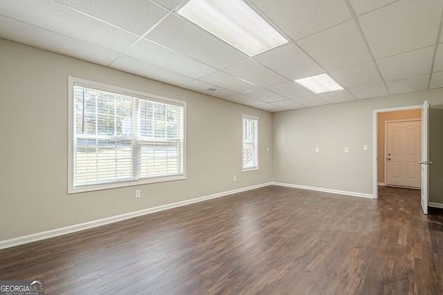 spare room featuring dark hardwood / wood-style floors and a drop ceiling