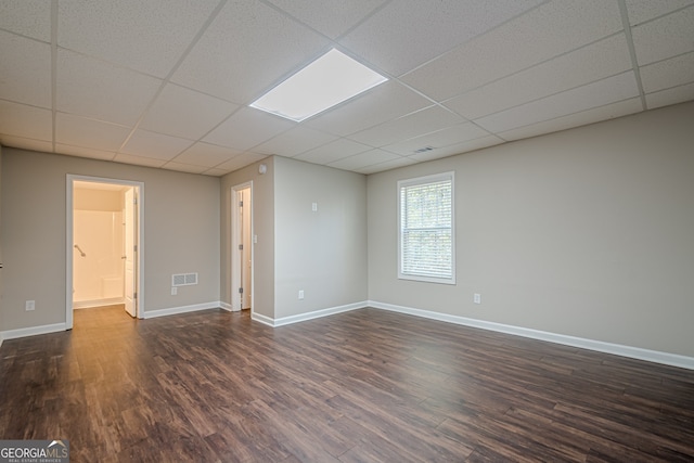 unfurnished room with dark hardwood / wood-style floors and a drop ceiling