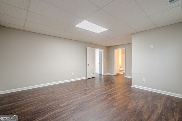 unfurnished room with dark hardwood / wood-style flooring and a drop ceiling