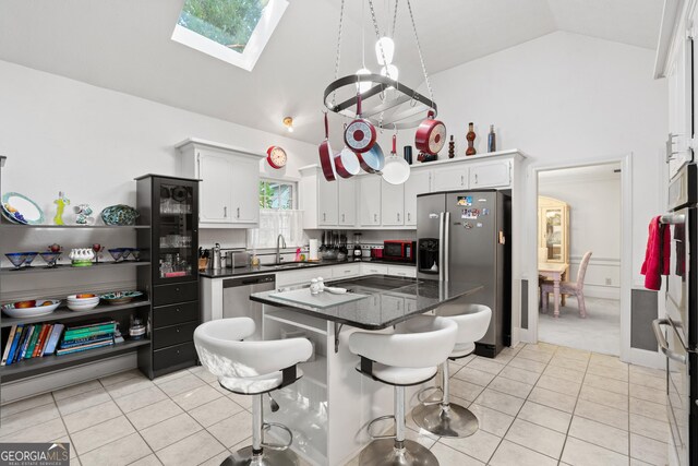 kitchen featuring a kitchen island, sink, a healthy amount of sunlight, and white cabinetry