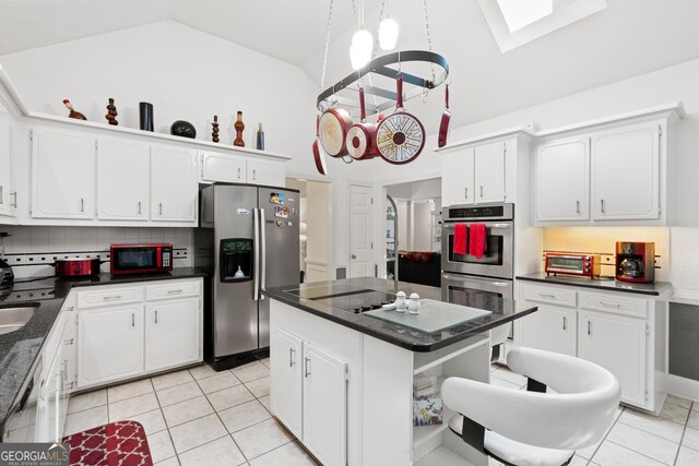 kitchen with vaulted ceiling with skylight, appliances with stainless steel finishes, sink, and white cabinetry