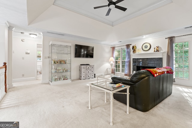 carpeted living room featuring ceiling fan, a fireplace, crown molding, and a raised ceiling