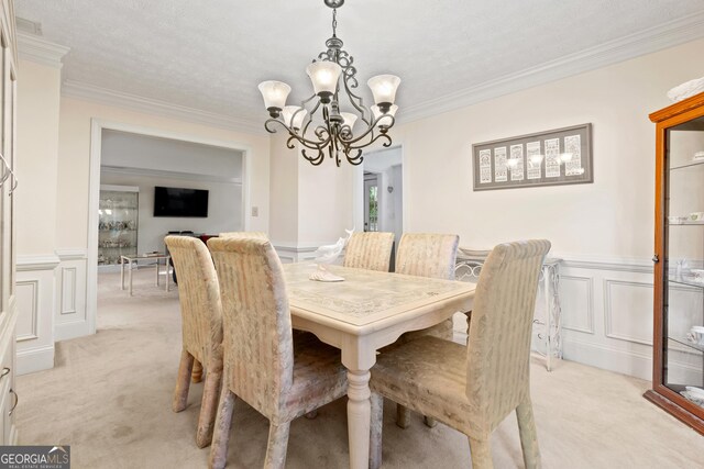 dining area with ornamental molding, a chandelier, a textured ceiling, and light carpet